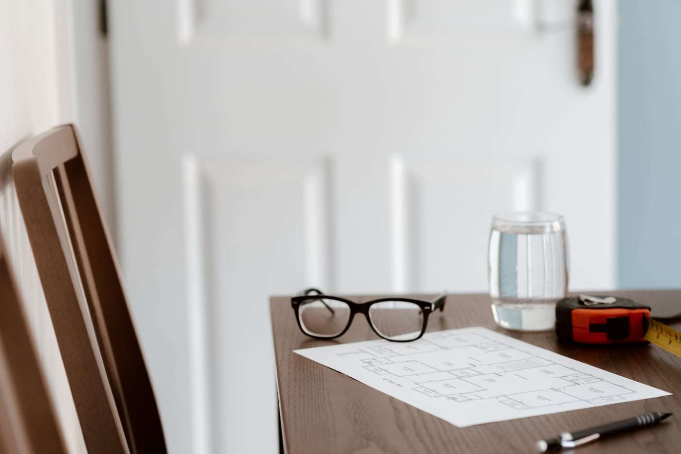 Grundriss mit Brille und Stift auf einem Holztisch