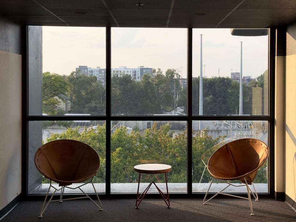Zwei Sessel mit Beistelltisch vor einer großen Fensterfront mit Blick ins Grüne